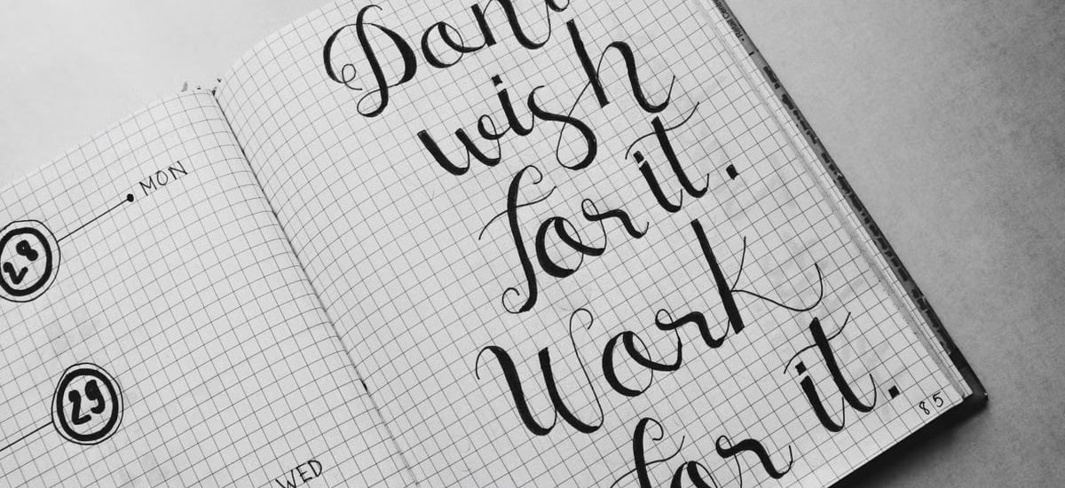 Close-up of motivational calligraphy on grid paper, inspiring message for productivity.