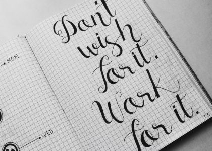 Close-up of motivational calligraphy on grid paper, inspiring message for productivity.